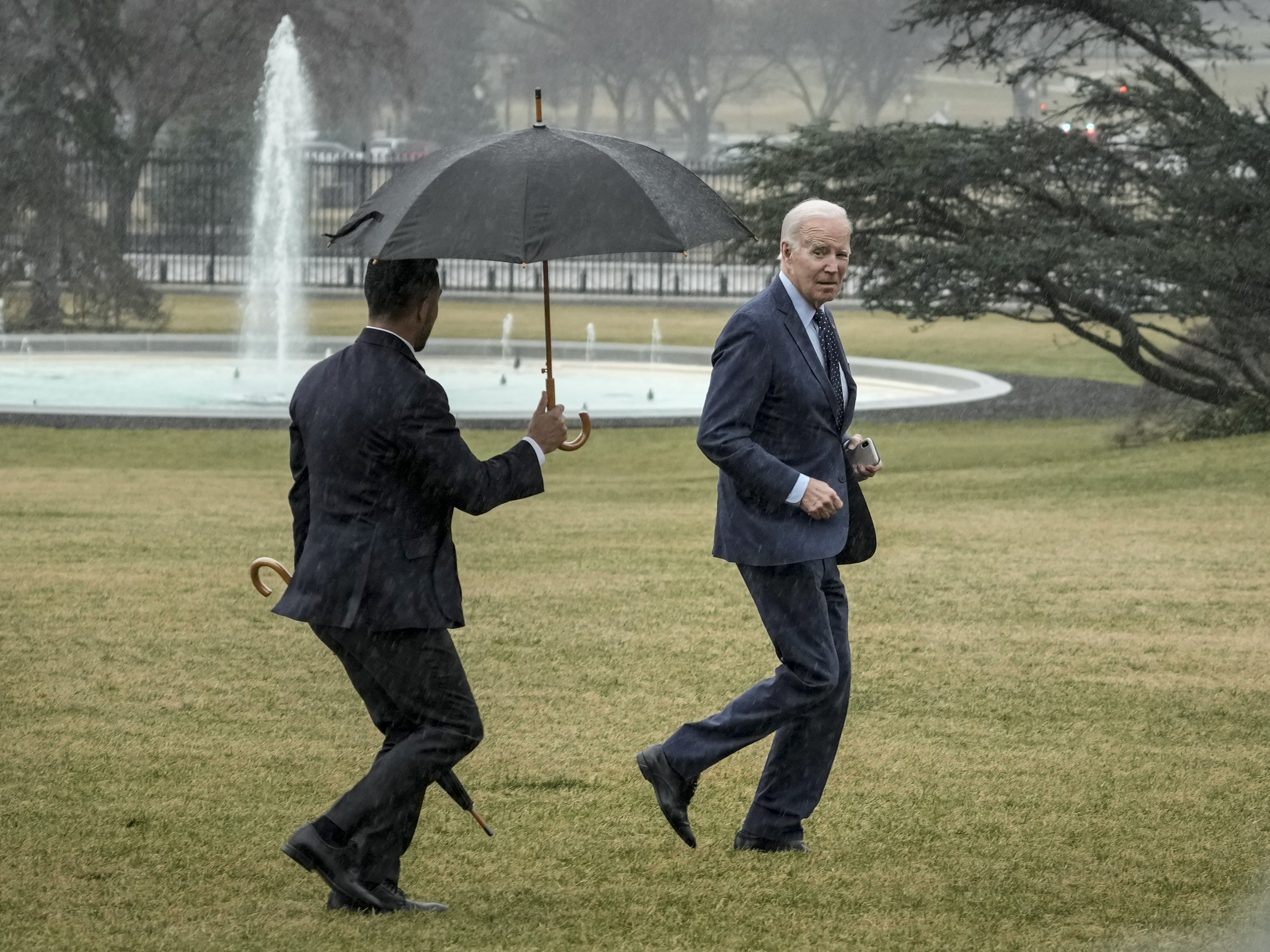 caption: President Biden jogs across the South Lawn of the White House in the rain after getting his latest physical on Feb. 16.