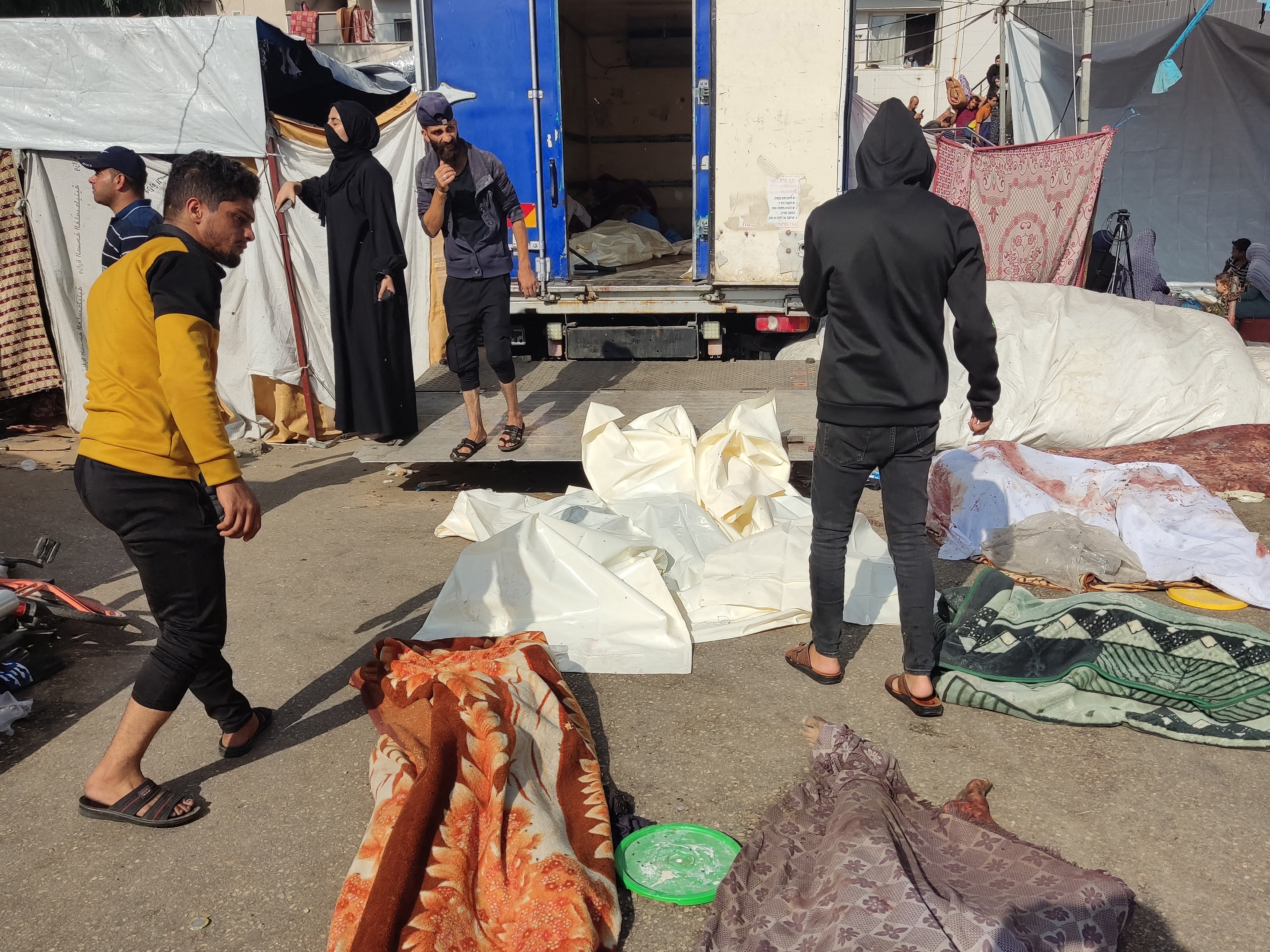 caption: People check the bodies of victims killed in a reported Israeli strike, as they lie on the ground in the vicinity of Gaza City's Al Shifa hospital compound on Friday.