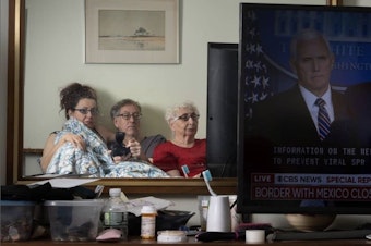 caption: Sophia Lansky, Neil Kramer and Kramer's mother, Elaine, watch the news in March 2020, from their two-bedroom apartment in Queens.