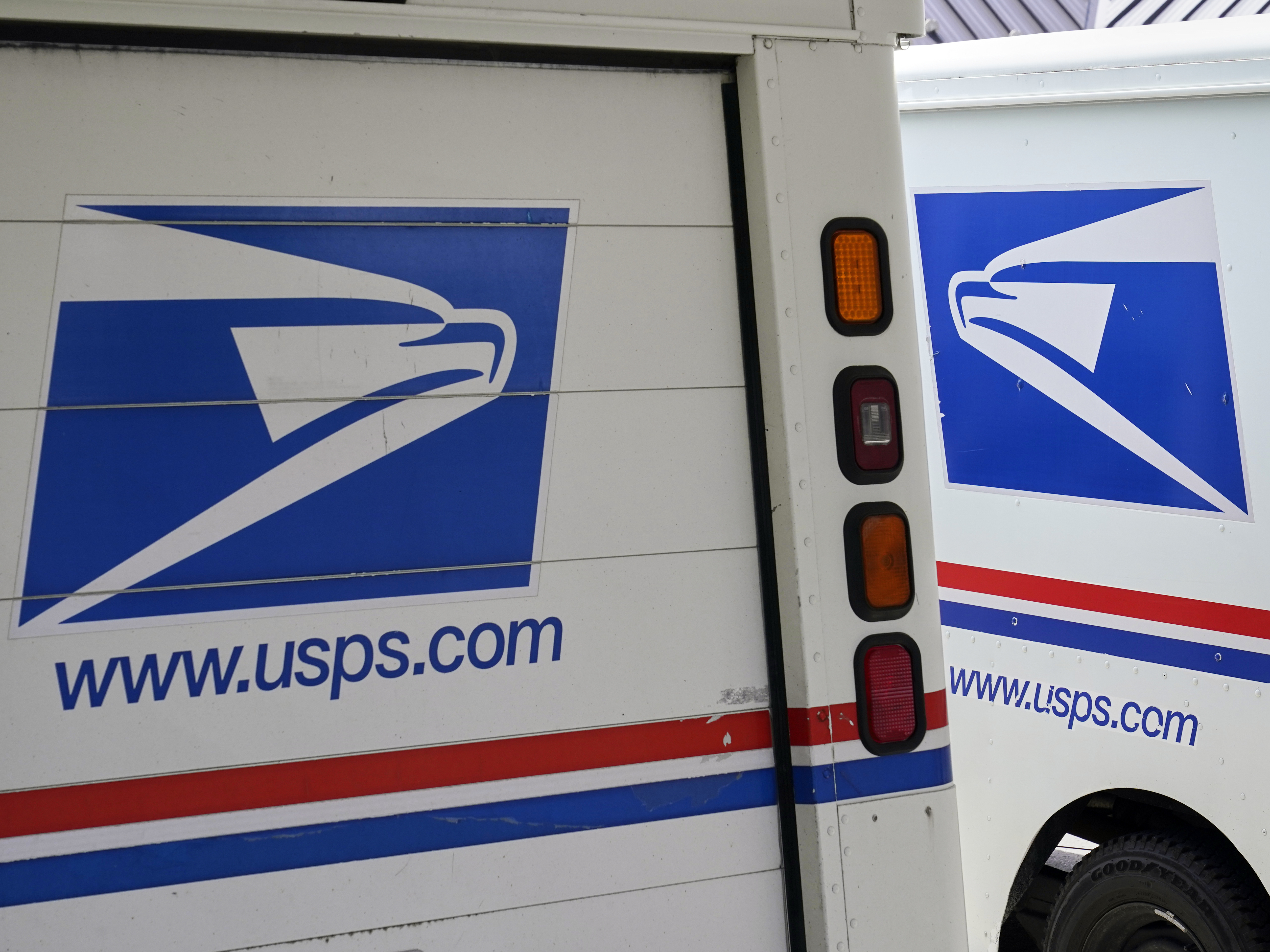 caption: Mail delivery vehicles are parked outside a post office in Boys Town, Neb., on Aug. 18, 2020. The Postal Service said Tuesday it will sharply increase the number of electric-powered delivery trucks in its fleet and will go all-electric for new purchases starting in 2026.