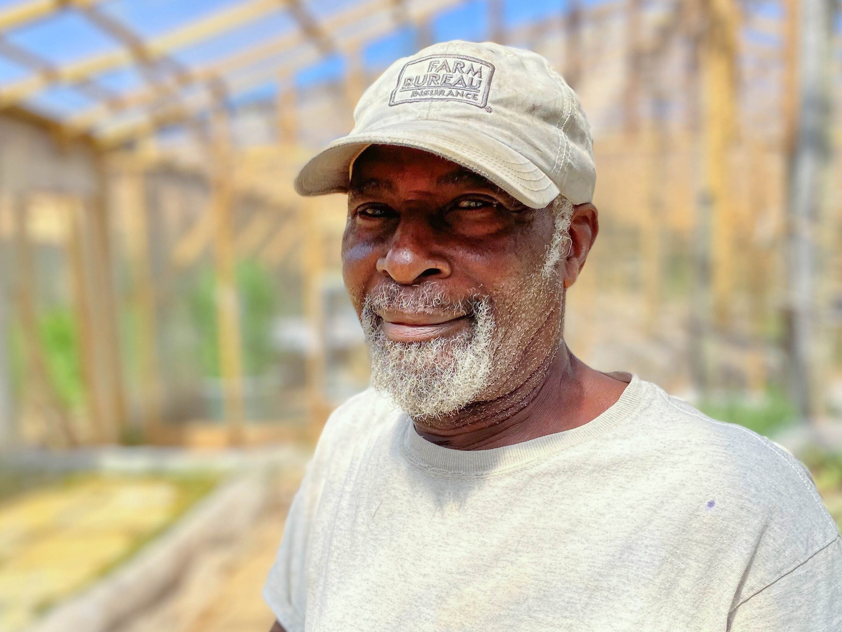 caption: Phillip Barker, in the hydroponic growhouse on Olusanya Farm LLC, which he owns with his wife in Oxford, N.C.