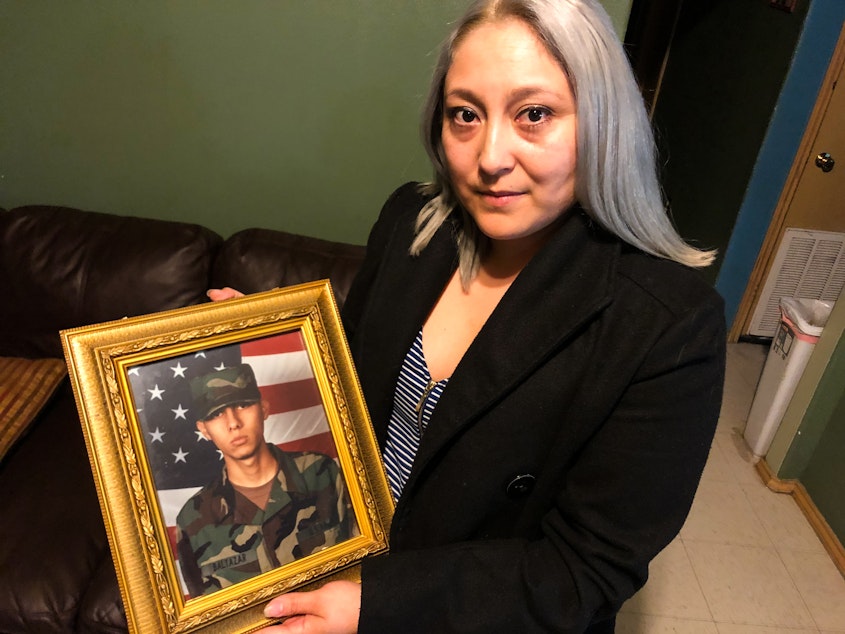 caption: Edgar Baltazar Garcia's wife, Jennifer Garcia, holds a photo of her husband from when he was deployed at Balad Air Base in Iraq as a turret gunner in a Humvee. He now faces deportation to Mexico over a felony conviction.