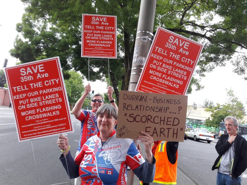 caption: Protesters wave signs opposing Seattle Department of Transportation plan to eliminate parking in favor of bike lanes on 35th ave NE. 