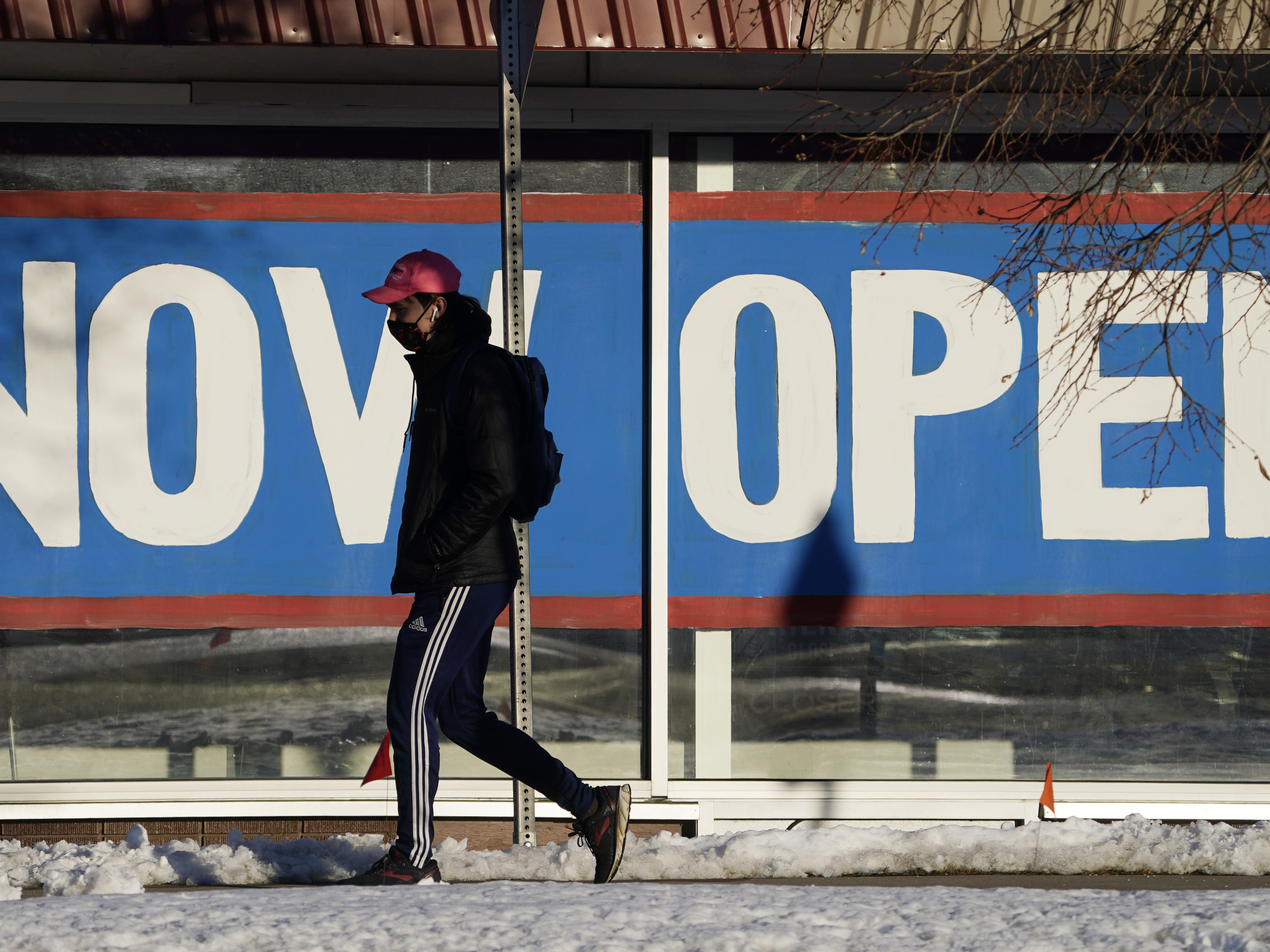 caption: A pedestrian on Feb. 25 walks past the window of a restaurant with a sign promoting its re-opening in Boulder, Colo. Congress on Wednesday passed a $1.9 trillion stimulus plan, which is expected to provide a strong boost to economic growth.