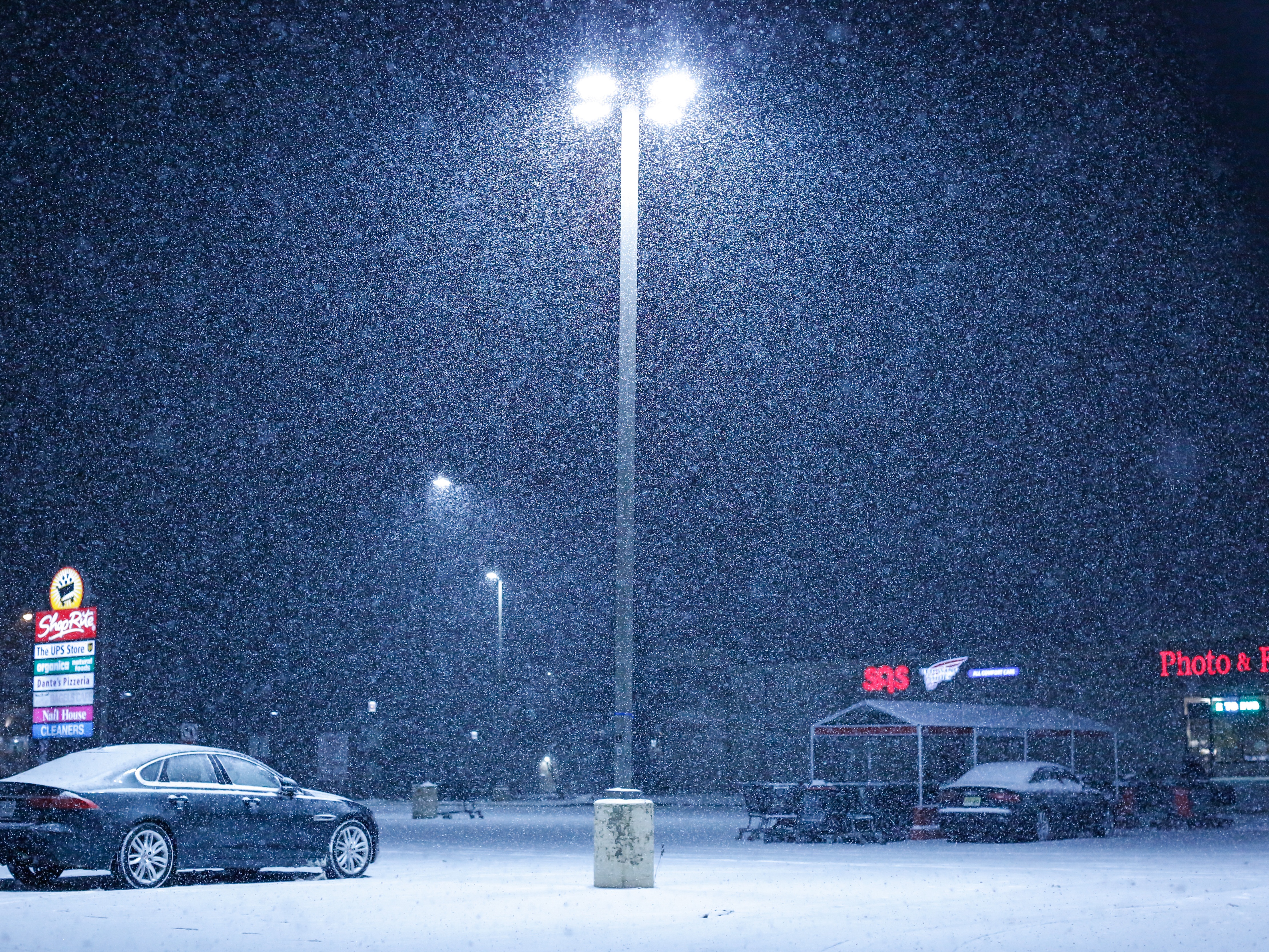 caption: Snow falls on an empty parking lot outside a supermarket in December in Northvale, N.J. Social media weather forecasters span a wide range of reliability — from amateurs with no science background to accredited meteorologists.