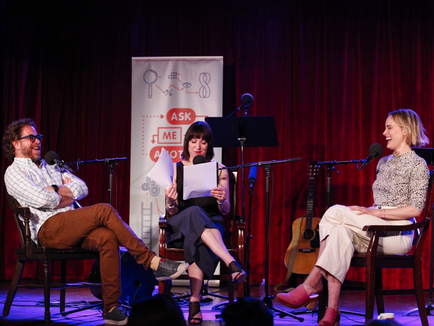 caption: Jonathan Coulton, Ophira Eisenberg and Taylor Schilling play a game on<em> Ask Me Another</em> at the Bell House in Brooklyn, New York.