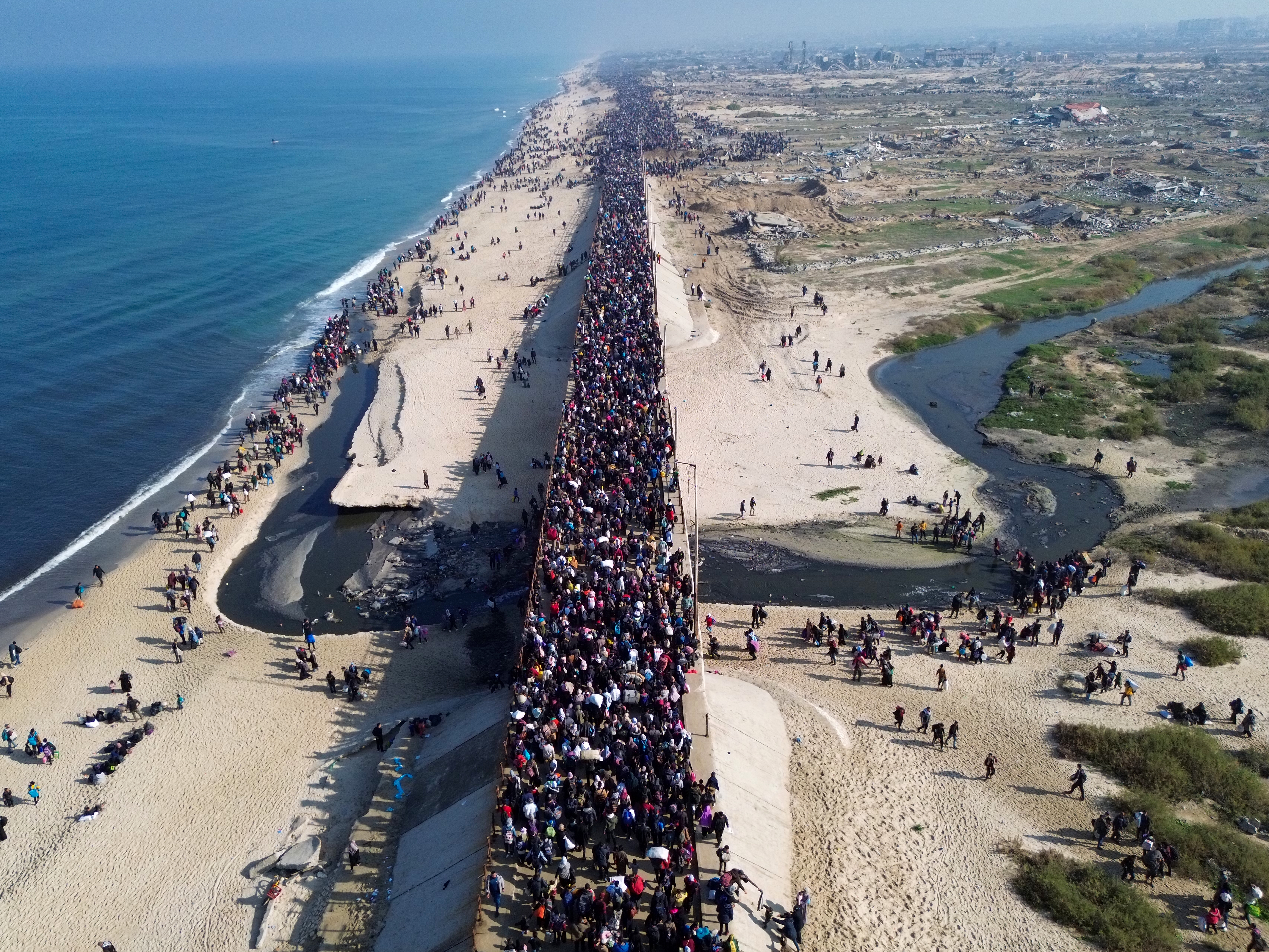 caption: This aerial photo shows displaced Gazans walking toward Gaza City on Jan. 27, 2025, after crossing the Netzarim corridor from the southern Gaza Strip.