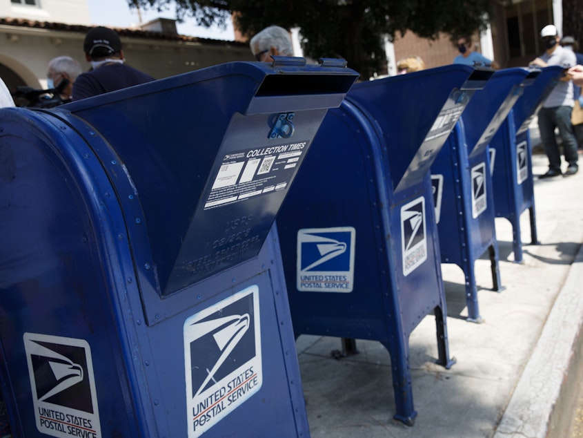 caption: A customer deposits mail into a U.S. Postal Service mail collection box in Burbank, Calif., on Tuesday.