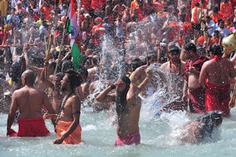 caption: Men take a holy dip in the Ganges River on the occasion of first royal bath of Shivratri festival during Maha Kumbh Festival in Haridwar, India.