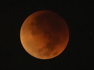 caption: A total lunar eclipse graces the night skies during the first blood moon of the year, in Brasilia, Brazil, Sunday, May 15, 2022.