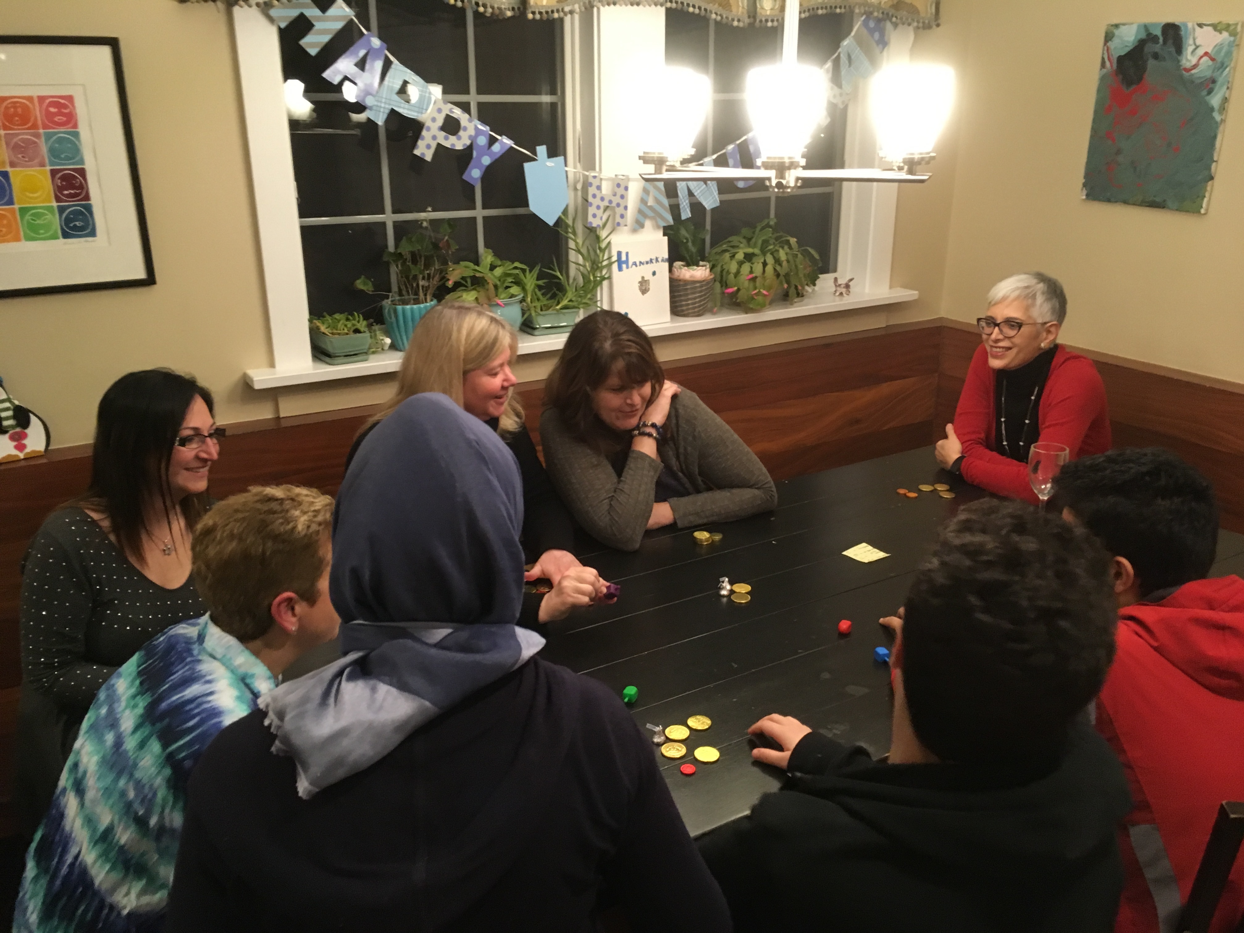 caption: Tilko, a refugee from Iraq (at center with her back to the camera), at a Hanukkah celebration on Dec. 4, 2018, with the Jewish volunteers who helped her resettle in America.