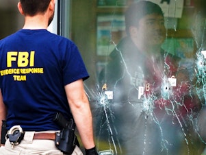 caption: Investigators work the scene of a shooting at a supermarket, in Buffalo, N.Y., on Monday.