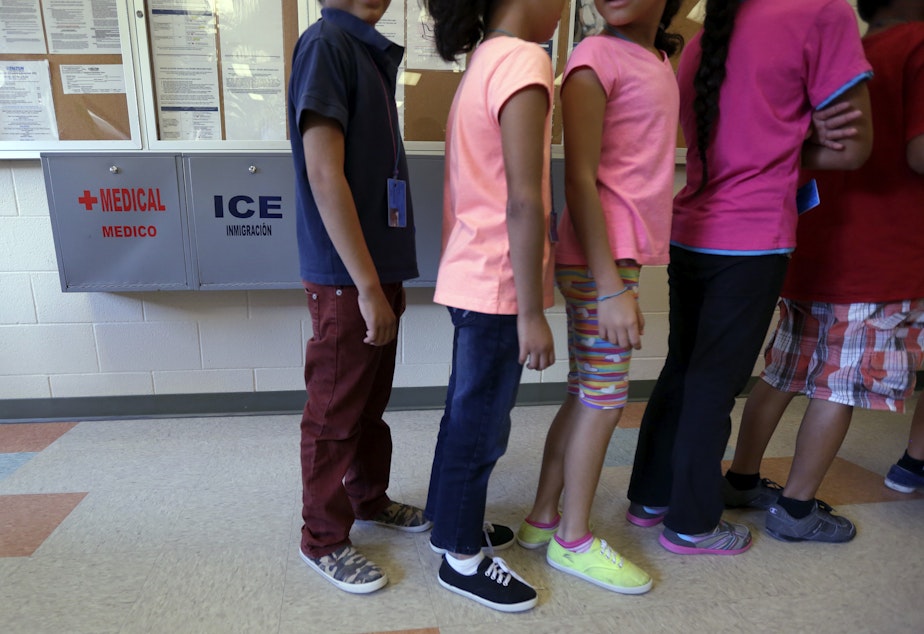 caption: In this Sept. 10, 2014 file photo, detained immigrant children line up in the cafeteria at the Karnes County Residential Center in Texas.