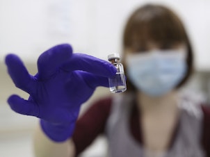 caption: A National Health Service pharmacy technician at the Royal Free Hospital in London simulates the preparation of the Pfizer vaccine Friday for support staff training ahead of this week's rollout.