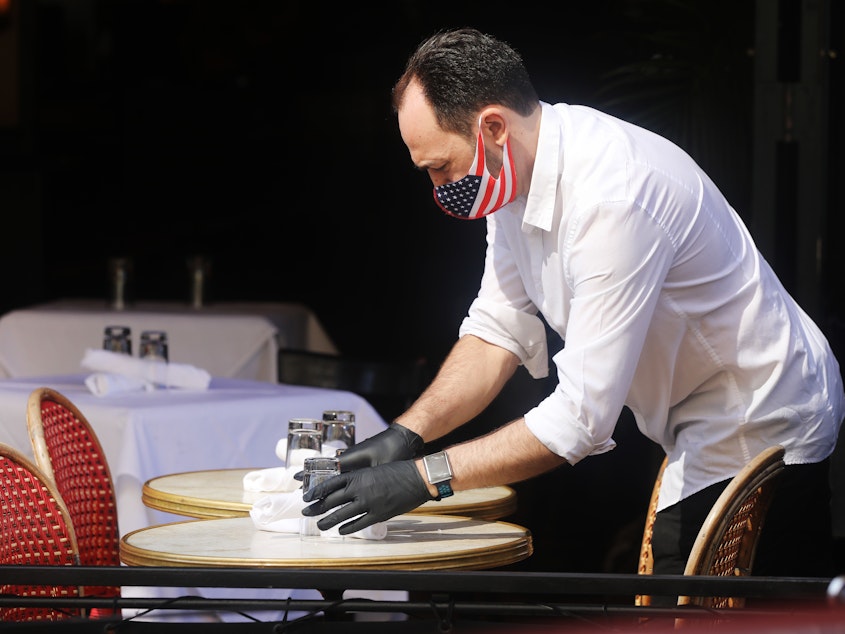 caption: A restaurant server in New York prepares a table.