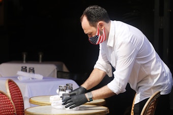 caption: A restaurant server in New York prepares a table.