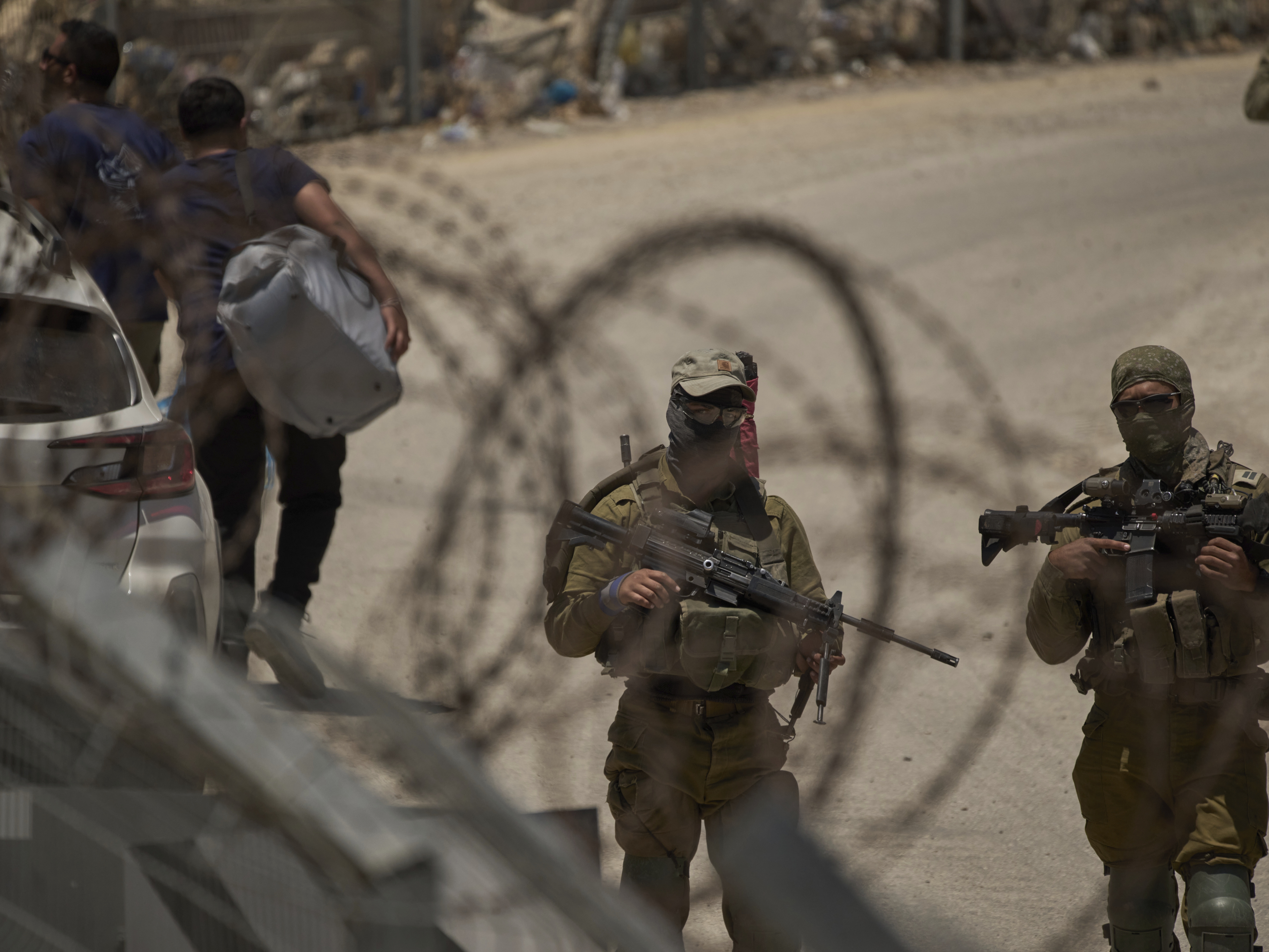 caption: Israeli soldiers stand guard as Syrian Druze people cross back into Syria at the Israeli-Syrian border, in the Israeli-controlled Golan Heights town of Majdal Shams, on Thursday.