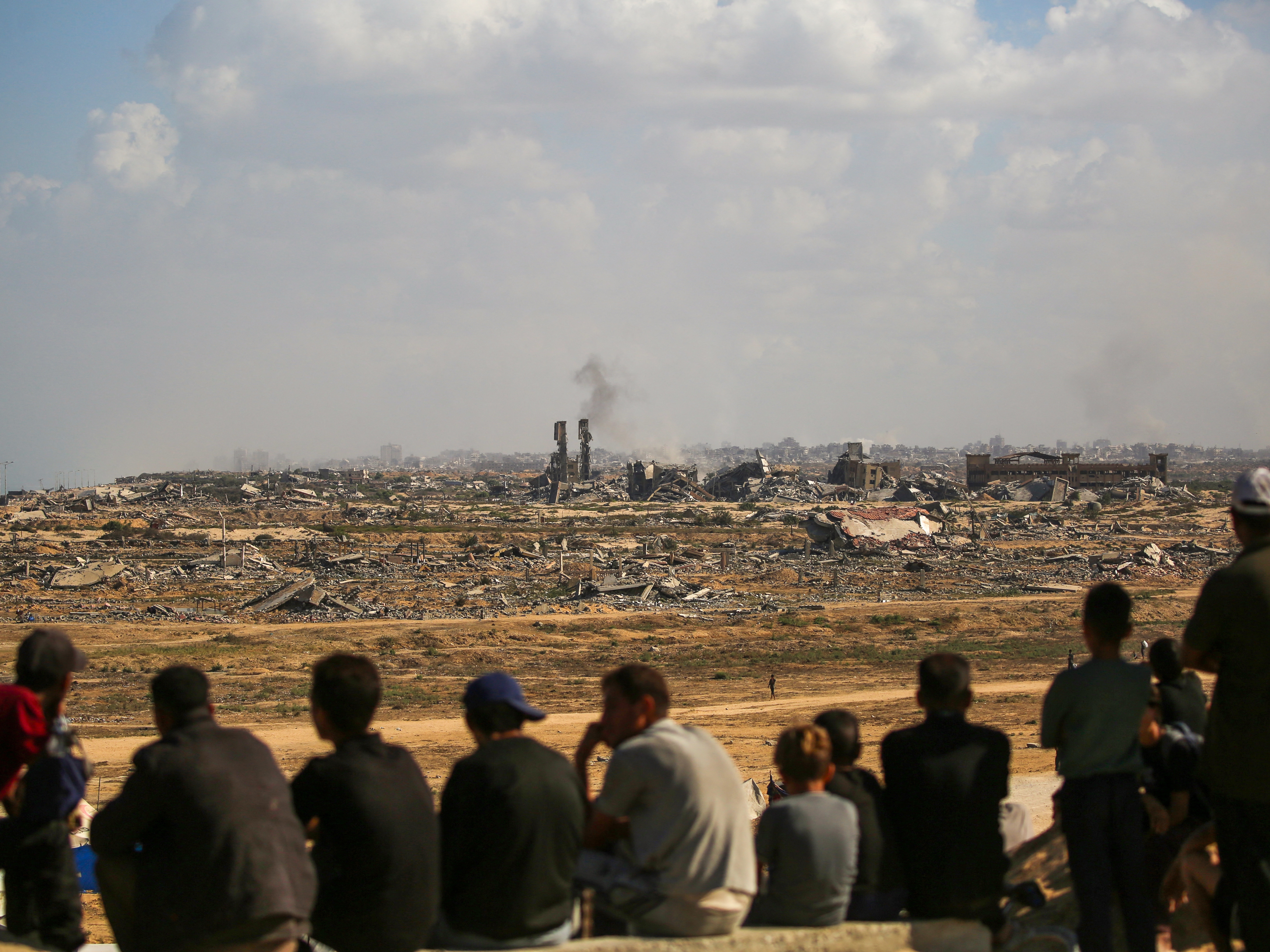 caption: Palestinians look toward Gaza City from Nuseirat in the central Gaza Strip on Friday. Gaza's civil defense agency said Friday that Israeli forces have begun pulling back from parts of the territory, particularly in Gaza City and Khan Younis.