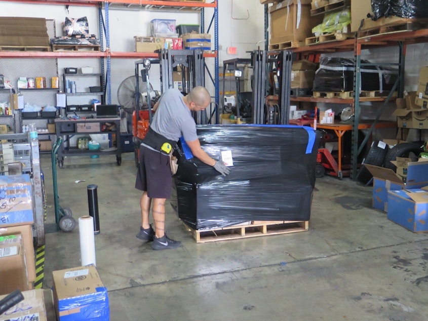 caption: A worker at VKE Cargo in Miami prepares a pallet containing cargo to be shipped to Venezuela. Fewer shipping companies are willing and able to ship to Venezuela.
