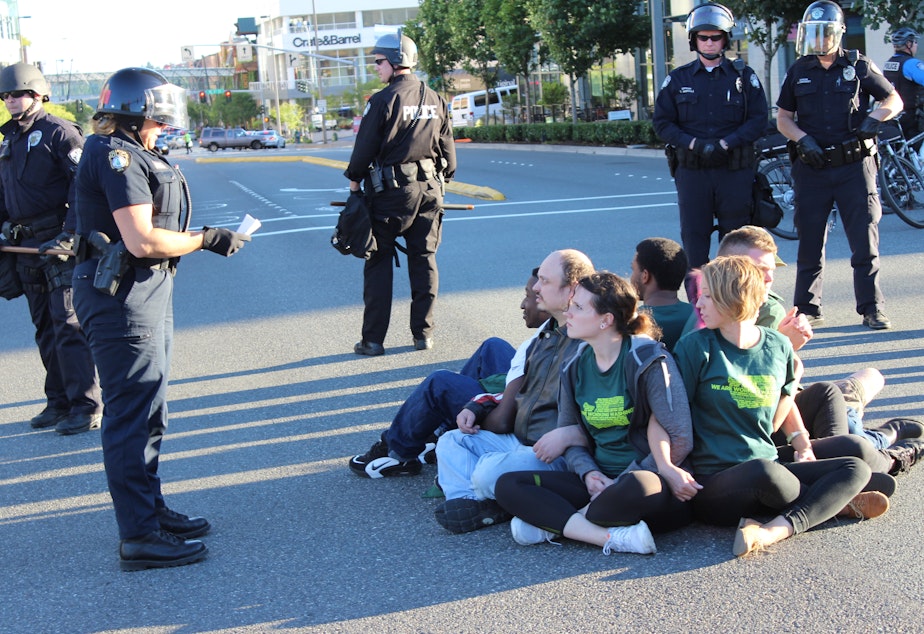caption: Bellevue police prepare to arrest eight minimum wage activists blocking a downtown intersection.