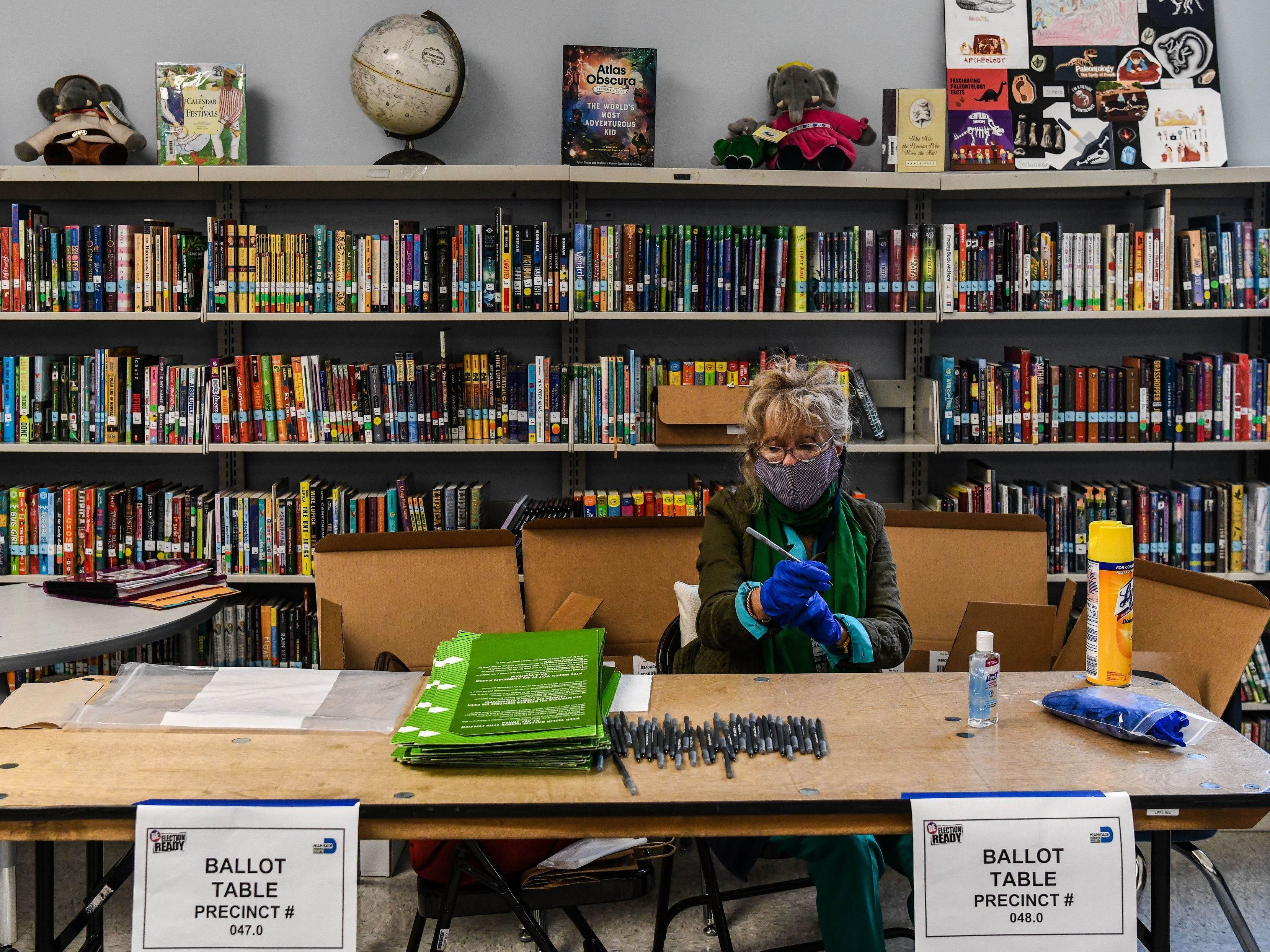 caption: An election worker wears protective gloves during the Florida primary election at South Pointe Elementary School in Miami, on Tuesday.