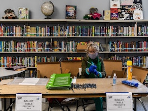 caption: An election worker wears protective gloves during the Florida primary election at South Pointe Elementary School in Miami, on Tuesday.