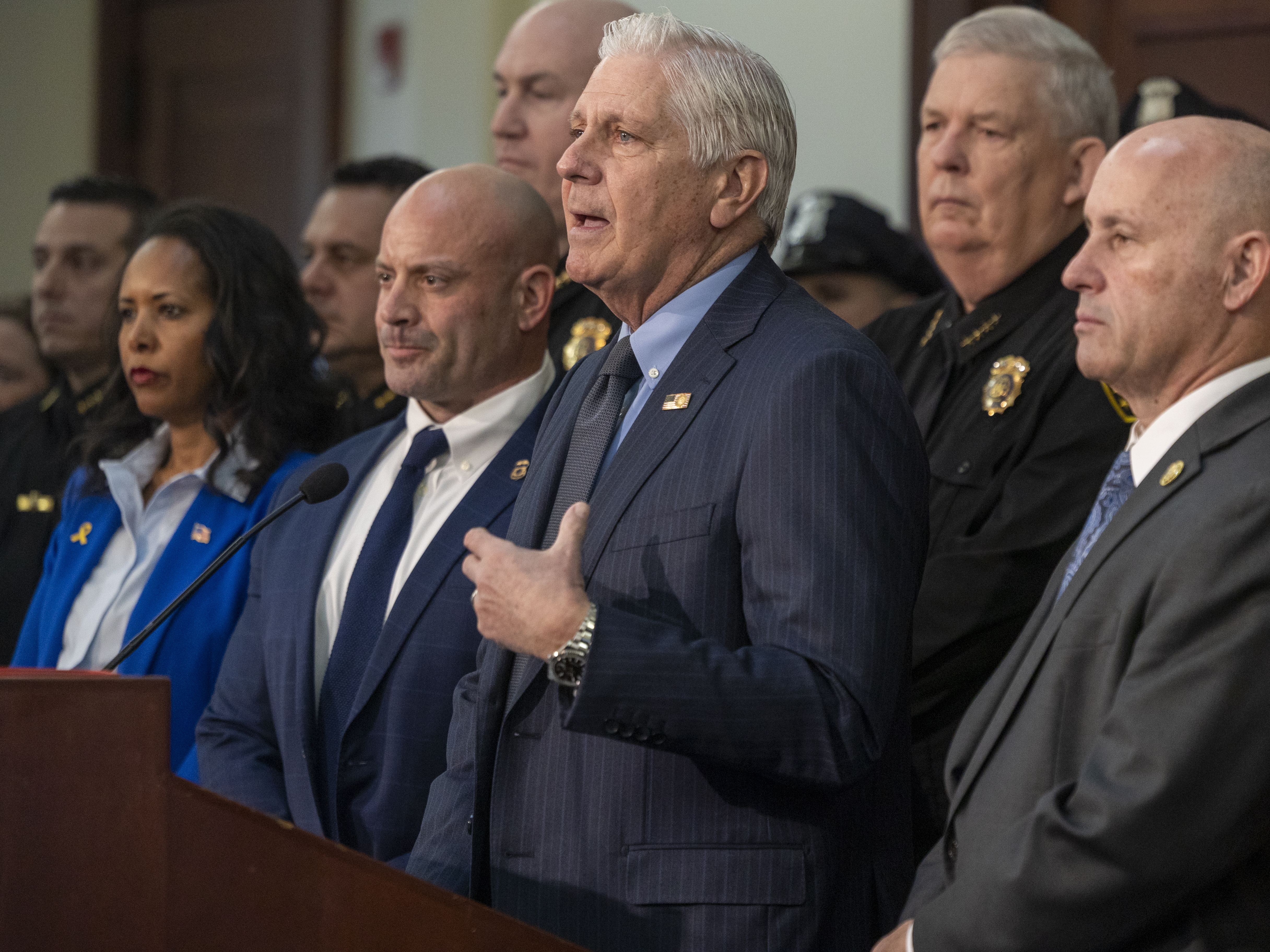 caption: Nassau County Executive Bruce Blakeman, flanked by local police and federal officials, announces an agreement to "cross-designate" ten police detectives as ICE agents