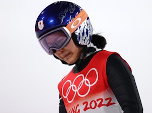 caption: Sara Takanashi of Team Japan shows dejection after being disqualified after jumping in the final round of the mixed team ski jumping event at the National Ski Jumping Center in Zhangjiakou, China.