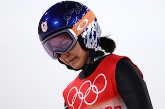 caption: Sara Takanashi of Team Japan shows dejection after being disqualified after jumping in the final round of the mixed team ski jumping event at the National Ski Jumping Center in Zhangjiakou, China.