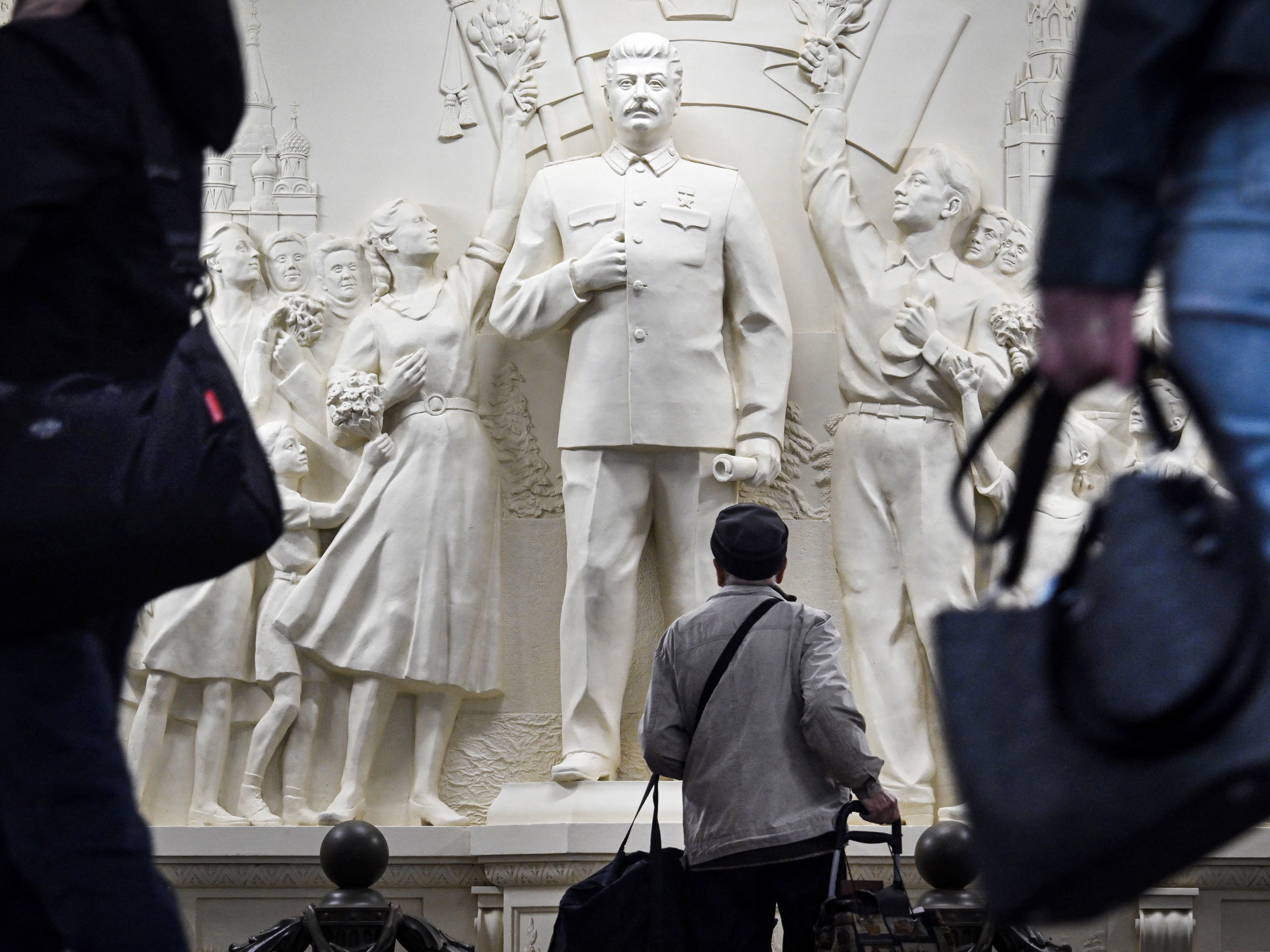 caption: Commuters pause walking past the newly unveiled high relief depicting Soviet dictator Josef Stalin in a passage at Taganskaya metro station in Moscow on May 15, 2025.