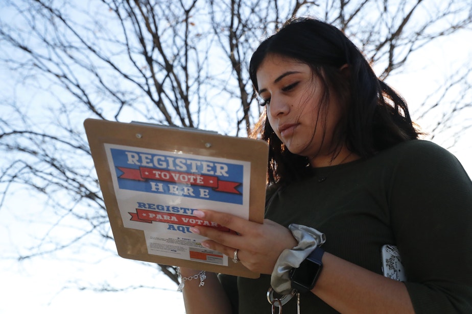 caption: Karina Shumate, 21, a college student studying stenography, fills out a voter registration form in Richardson, Texas, on Jan. 18, 2020.