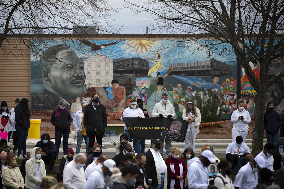 caption: A crowd gathers at People's Park on Sunday, February 28, 2021, following a silent march ahead of the one-year mark of the Tacoma police killing of 33-year-old Manuel Ellis who said, "I can't breathe, sir," before he died, on Martin Luther King Jr. Way in Tacoma.