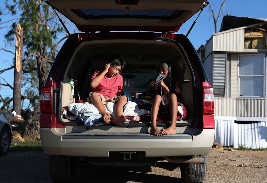 caption: Carlos and Jessica Deviana sit in the back of their father's SUV, which they were using as a bedroom after Hurricane Michael destroyed their home in Panama City, Fla., in October 2018.