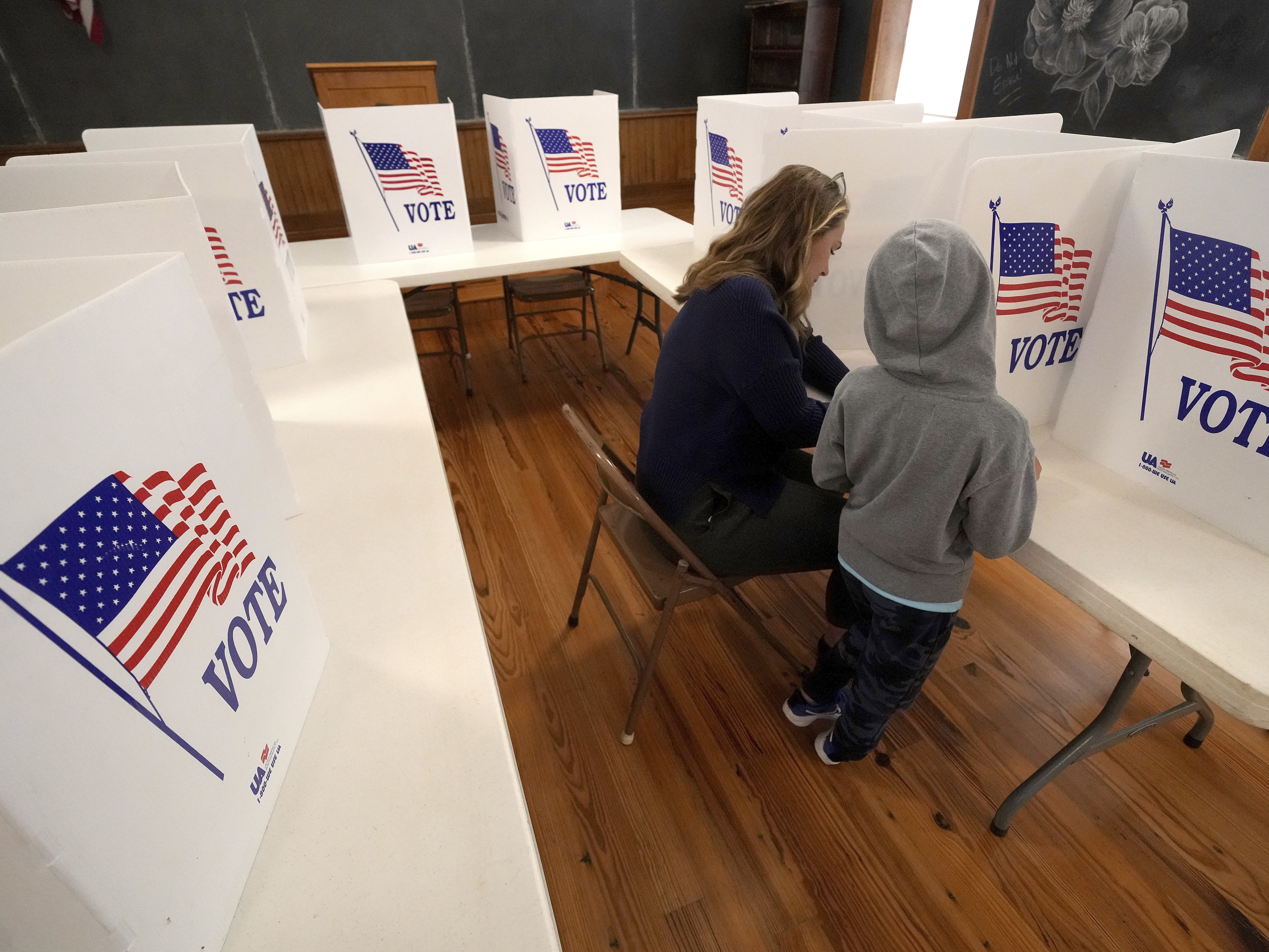 caption: Aliza Bidinger is accompanied by her son Jayce, age 6, as she votes at the 146-year-old Buck Creek school on Election Day, Tuesday, Nov. 5, 2024, in rural Perry, Kan. (AP Photo/Charlie Riedel)