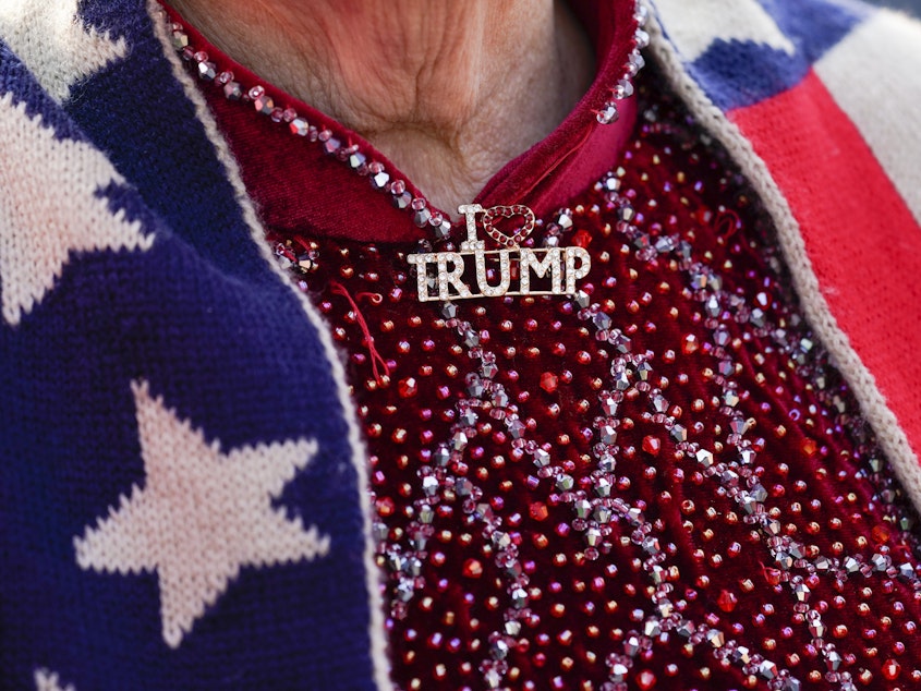 caption: A supporter of former President Donald Trump wears an "I Love Trump" pin while waiting for him to speak at Trump National Golf Club in Bedminster, N.J., Tuesday.