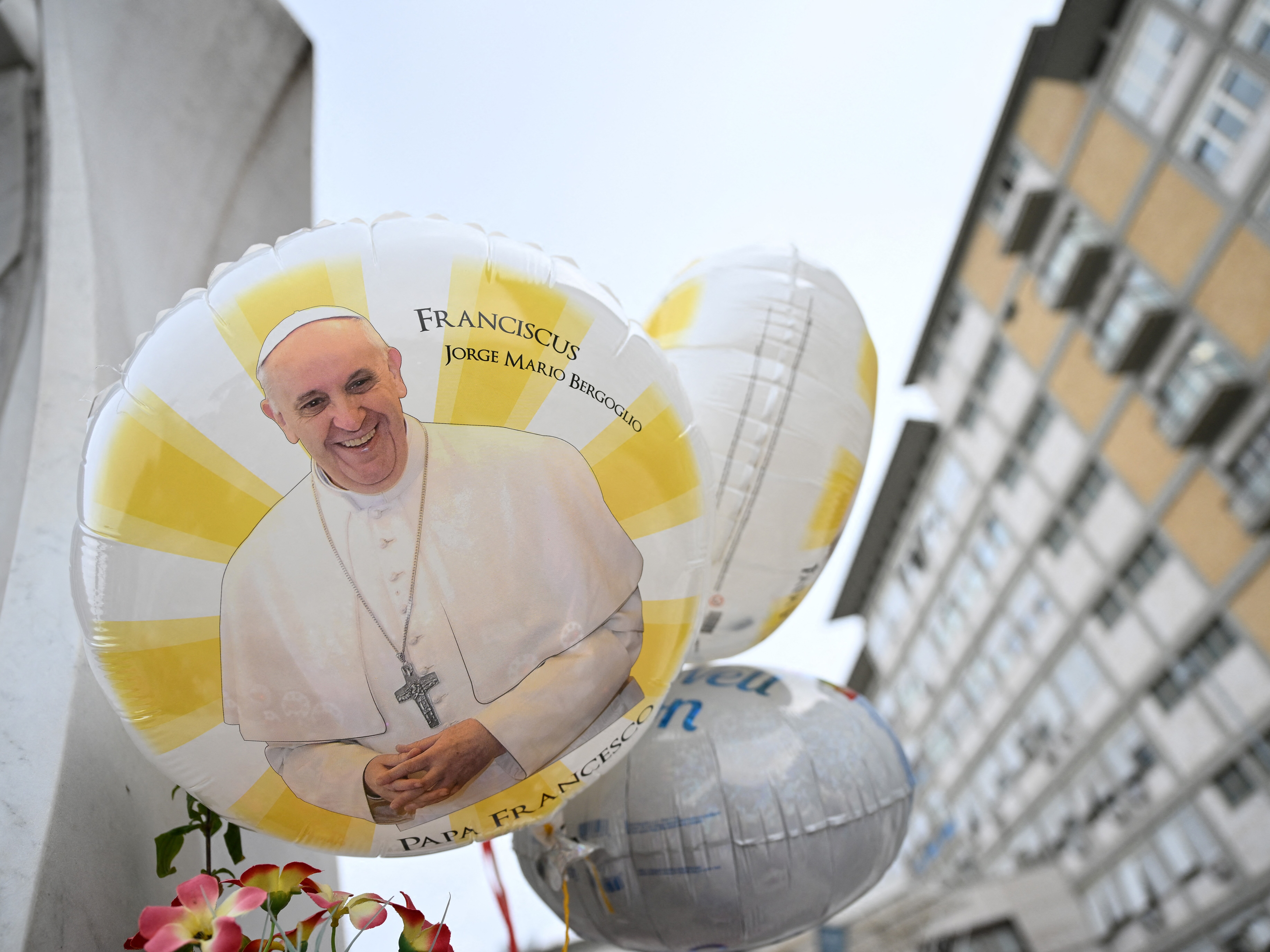 caption: Balloons depicting Pope Francis are laid at the statue of John Paul II outside the Gemelli hospital where Pope Francis is hospitalized, in Rome on Feb. 24, 2025. Pope Francis, in critical condition in hospital with pneumonia, had a good night and was resting, the Vatican said Monday.