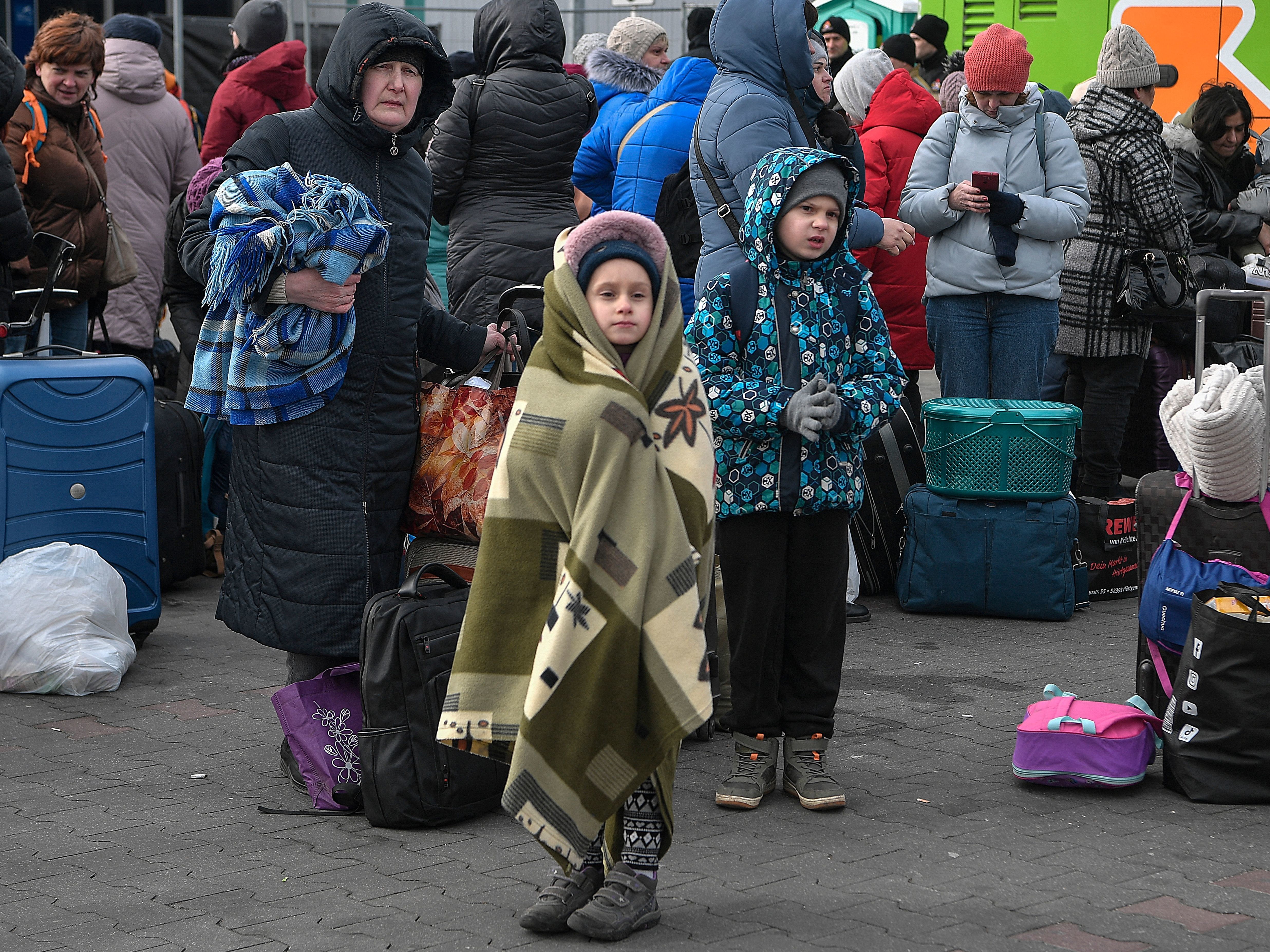 caption: People wait to board buses taking them further into Poland or abroad from a temporary refugee shelter in a former shopping center near the Polish city of Przemysl on Tuesday.