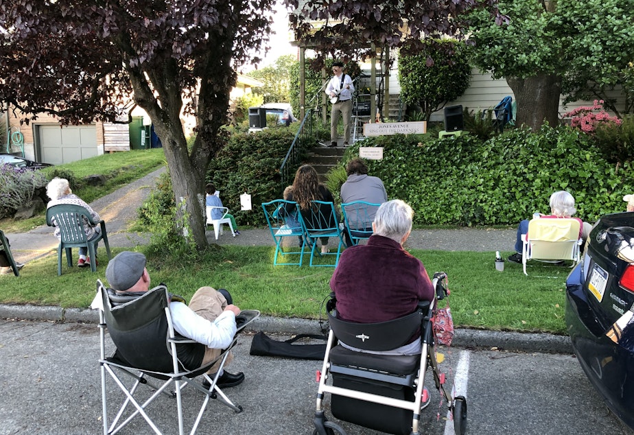 caption: Peter McKee playing banjo for his Ballard neighbors during the Covid-19 pandemic