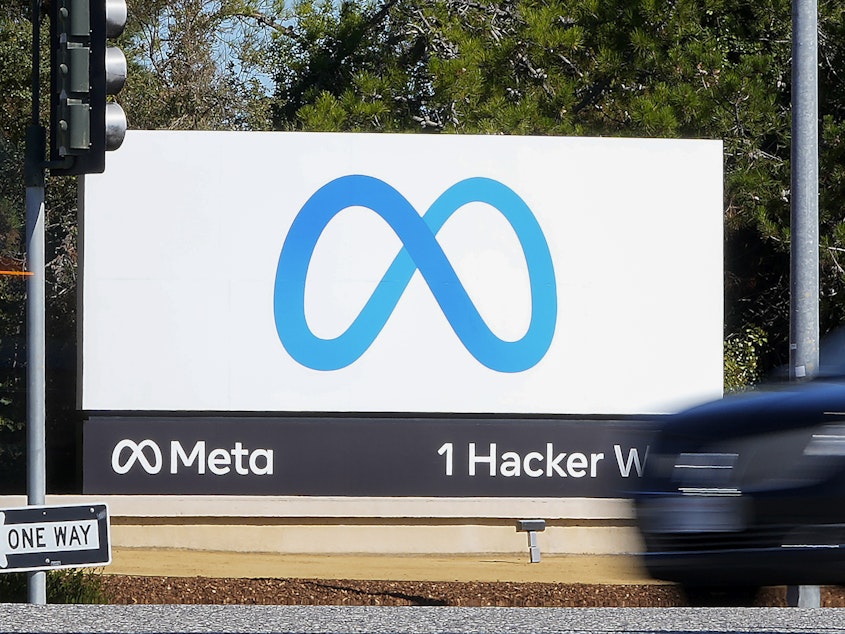 caption: A car passes Facebook's new Meta logo on a sign at the company headquarters in Menlo Park, Calif.