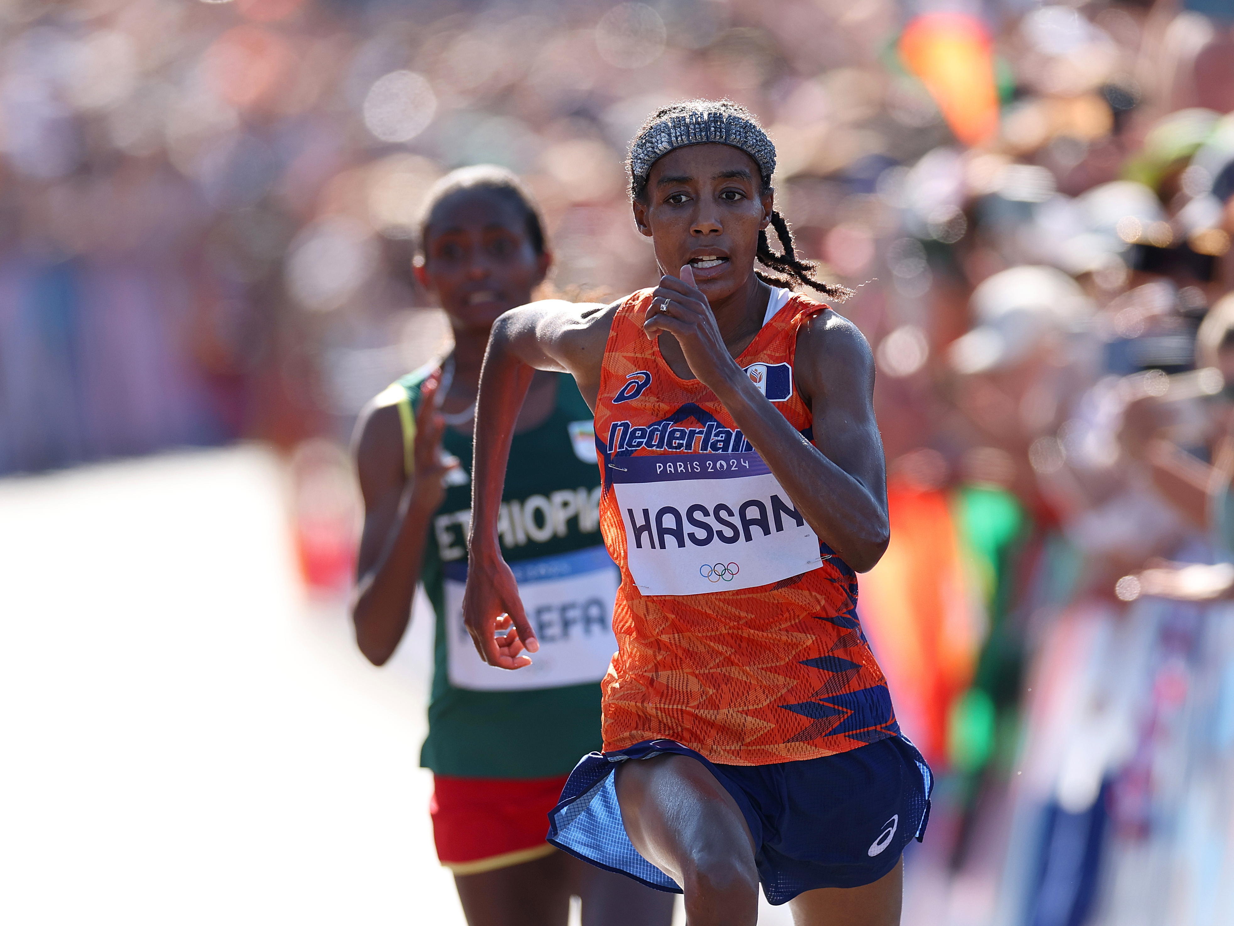 caption: Sifan Hassan of the Netherlands stays ahead of Ethiopia's Tigst Assefa at the finish of the women's marathon on Sunday at the Paris Olympics. Hassan won gold, adding to two bronzes she won in the 5,000 and 10,000 meter races.
