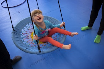 caption: Lillian Rockett, 4, laughs as she is pushed on a circular swing on Sunday, October 1, 2017, at We Rock the Spectrum Kid's Gym in Bellevue.