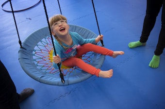 caption: Lillian Rockett, 4, laughs as she is pushed on a circular swing on Sunday, October 1, 2017, at We Rock the Spectrum Kid's Gym in Bellevue.