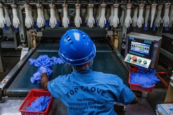 caption: A worker inspects disposable gloves at a factory in Malaysia, a country that has been the top supplier of medical gloves to the U. S. and which is facing increasing competition from China.