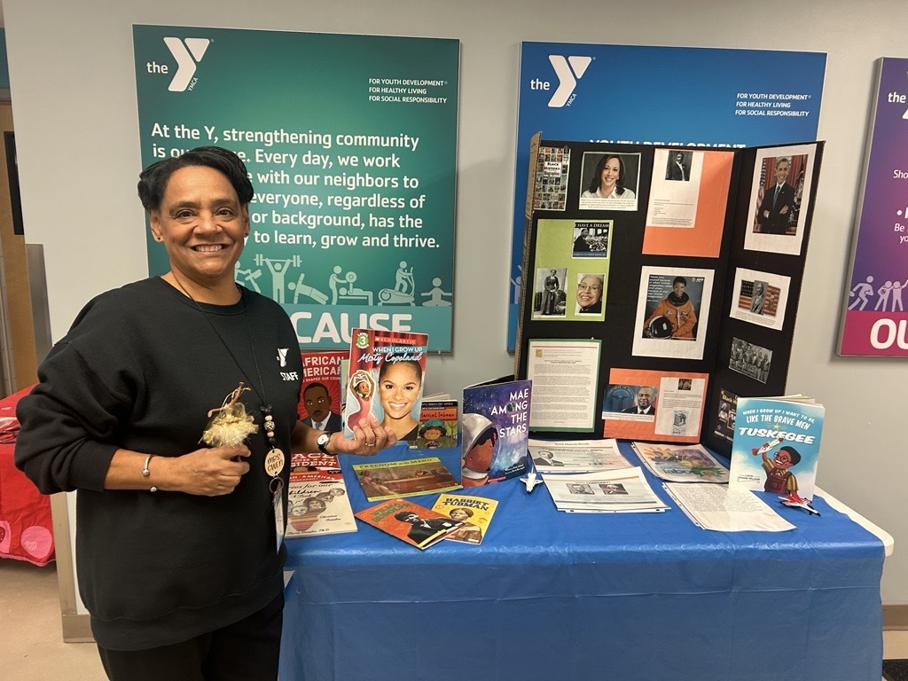 caption: Gwen Partridge, known to her students as "Mrs. Gwen," stands in front of an exhibit she created for Black History Month on Feb. 13. She's uncertain others will be able to continue teaching Black history once she retires given the Trump administration's orders that schools eliminate diversity initiatives or risk losing federal funding.