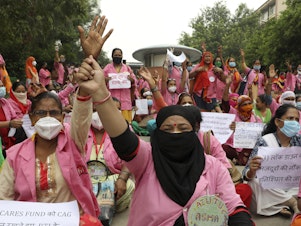 caption: Female community health care workers protest in New Delhi, India, in August 2020. The women are part of a government program called Accredited Social Health Activists — and are demanding higher pay and better working conditions. In May, the program won an award from the World Health Organization.