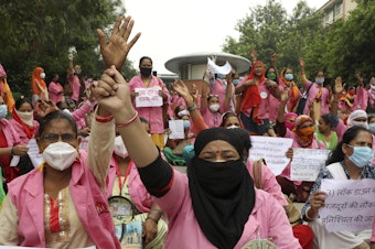 caption: Female community health care workers protest in New Delhi, India, in August 2020. The women are part of a government program called Accredited Social Health Activists — and are demanding higher pay and better working conditions. In May, the program won an award from the World Health Organization.