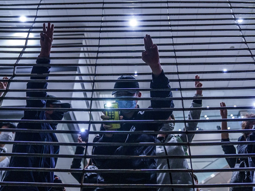 caption: Pro-democracy demonstrators gesture with three-fingered salutes outside West Kowloon Magistrates Courts during a hearing for opposition activists charged with violating the city's national security law in Hong Kong Thursday, March 4, 2021. All 47 of the pro-democracy activists in a Hong Kong subversion case returned to custody Thursday after a marathon hearing ended with them being denied bail.