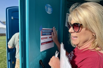 caption:  JoDee Garretson, executive director of the Support, Advocacy and Resource Center, tapes up a flyer for people to tear off tabs with SARC's phone number on them. The agency helps survivors of sexual abuse and human trafficking.&#13;