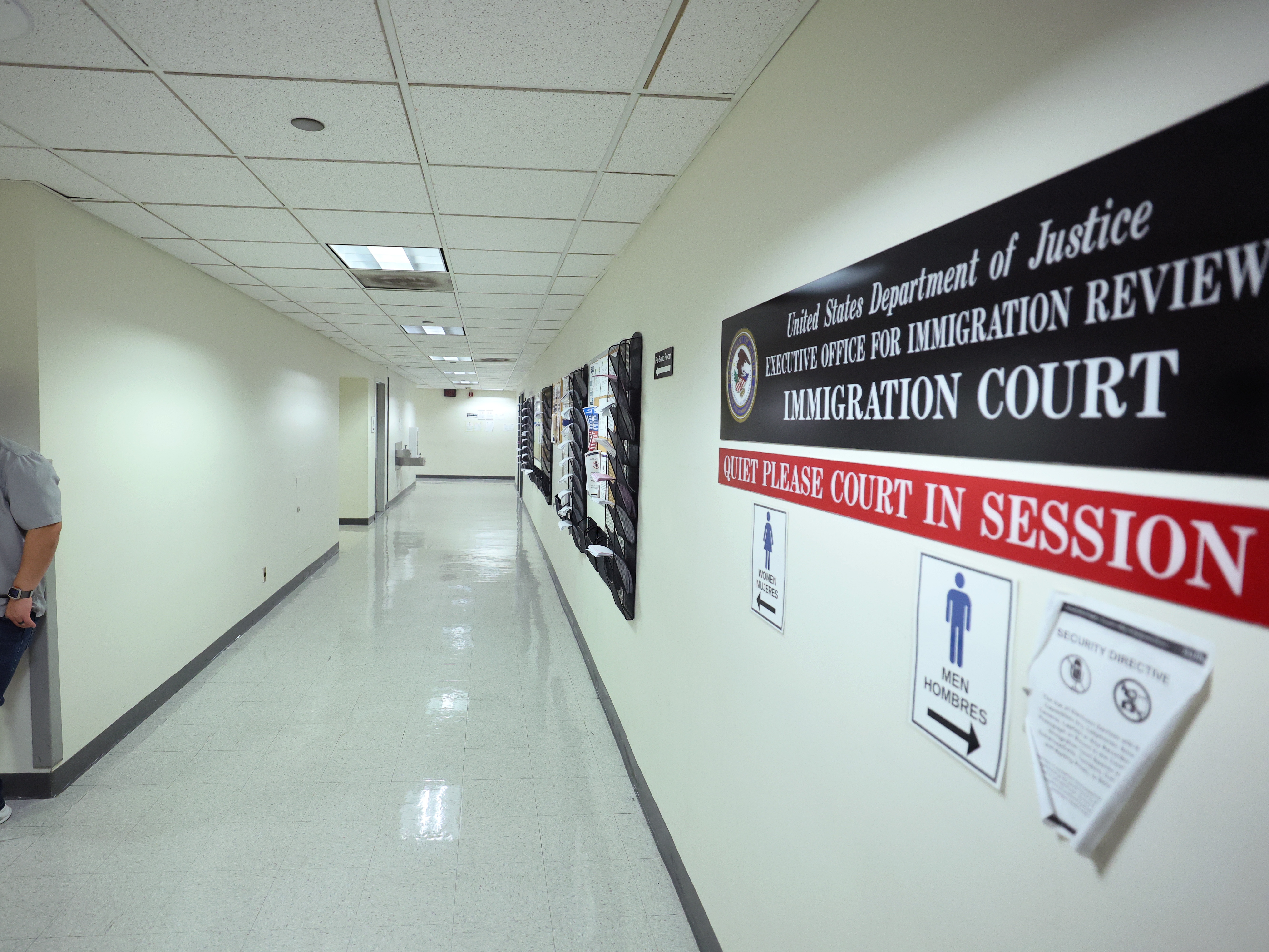 caption: Federal agents patrol the halls of immigration court at the Jacob K. Javitz Federal Building on Aug. 28.