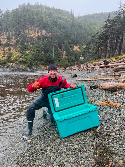 caption: Gwaii Haanas Park Reserve and Haida Heritage Site scientist Geoff Martynuik celebrates after finding an expensive cooler washed up on the west coast of Haida Gwaii on Oct. 30, 2021. 